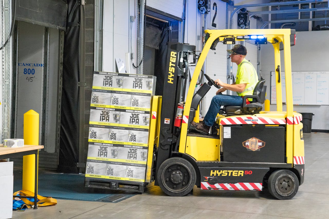 Mastering the First Impression: Your intriguing post title goes here A worker drives a Hyster forklift moving Joe IPA boxes in a warehouse.